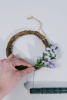 リース台にスターチスを沿わせながらワイヤーを巻き付けます