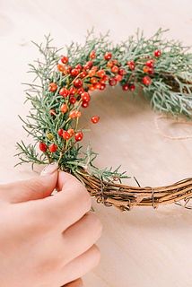 リース台に花材を沿わせながらワイヤーを巻き付けます